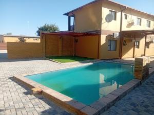 a swimming pool in front of a house at Otam-Check Guest House in Ondangwa