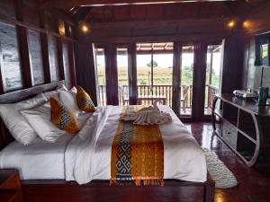 a bedroom with a large bed in a room with windows at Merlyn Meadows Retreat in Munduk