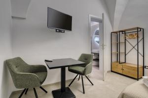 a room with two chairs and a table and a tv at Agrù - Salento Garden Stay in Cavallino di Lecce