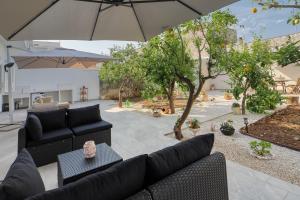 a patio with two black couches and an umbrella at Agrù - Salento Garden Stay in Cavallino di Lecce