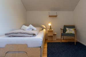 a bedroom with a bed and a chair and a lamp at Ferienwohnung Loipenblick in Obergesteln
