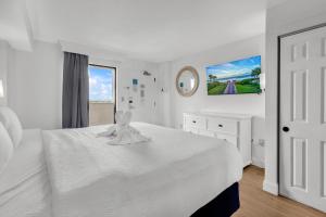 a white bedroom with a white bed and a window at Condos at the Caribbean Resort in Myrtle Beach
