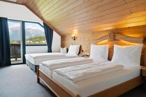 two beds in a room with a large window at Hotel Gruberhof Innsbruck Igls B&B in Innsbruck
