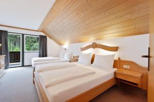 two beds in a room with wooden ceilings at Hotel Gruberhof Innsbruck Igls B&B in Innsbruck