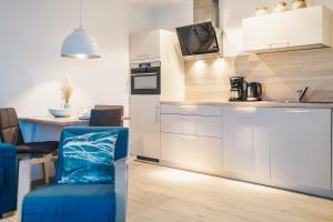 a kitchen with white cabinets and a blue chair at Am Park 3 in Prerow