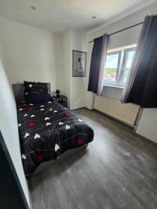 a bedroom with a bed with a black comforter and a window at Marien 2 Ferienwohnung Monteuerwohnung in Eppelborn
