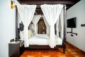 a bedroom with a canopy bed with white curtains at SVS Arena in Kizhake Chālakudi