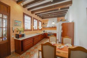 a large kitchen with a table and a refrigerator at Casa Angels in Pollença