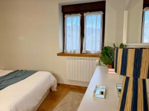 a bedroom with a bed and a table and windows at Monte Subiedes, Apartamentos Valle de Camaleño in Camaleño