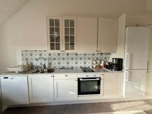 a kitchen with white cabinets and a sink and a refrigerator at Kinnekulle bed & breakfast in Källby