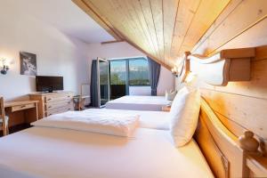a bedroom with two beds and a desk and a television at Hotel Gruberhof Innsbruck Igls B&B in Innsbruck