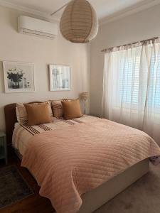 a large bed in a bedroom with a large window at Darlow Cottage in Wagga Wagga
