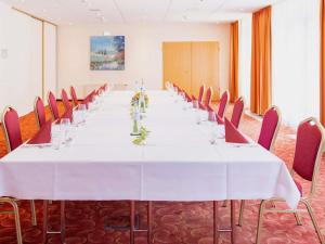 a long table in a room with red chairs at Mercure Hotel Plaza Magdeburg in Magdeburg