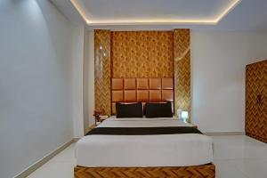 a bedroom with a large bed with a wooden headboard at Hotel O Skycity in Kānpur