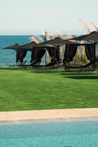 a group of tables with umbrellas next to the ocean at NOE Suites in Ayios Theodhoros