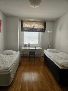 two beds in a room with a table and a window at Apartment Asemakatu 20 in Kuopio