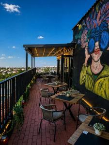 eine Terrasse mit Tischen und einem Gemälde an der Wand in der Unterkunft Hotel Reina in Bukarest