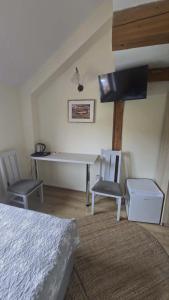 a bedroom with a bed and a desk and two chairs at Pokoje Gościnne w Spichlerzu in Ustka