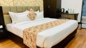 a bedroom with a large bed with white sheets at Hotel Rove Inn in Indore +1 photo