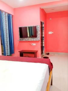 a bedroom with a red wall with a tv at BHS Deluxe Rooms in Puri