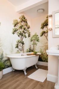 a bath tub in a bathroom with trees on the wall at Stylish Top Floor Retreat with Stunning Solent Views in Portsmouth +30 photos