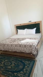 a bedroom with a large bed with a rug at Hotel Turi & Punjabi Restaurant in Rewalsar