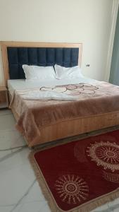 a bed with a blue headboard and a red rug at Hotel Turi & Punjabi Restaurant in Rewalsar
