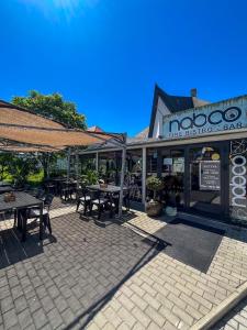 an outdoor patio with tables and umbrellas in front of a restaurant at Zöldház Panzió in Gyenesdiás