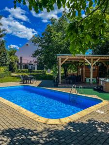 a swimming pool in a yard with a pergola at Zöldház Panzió in Gyenesdiás