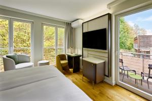 a hotel room with a bed and a large window at Bollants SPA im Park, Autograph Collection in Bad Sobernheim
