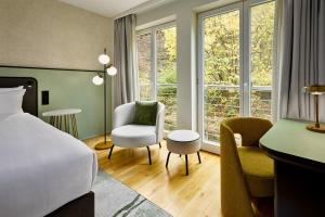 a hotel room with a bed and a desk and chairs at Bollants SPA im Park, Autograph Collection in Bad Sobernheim +45 photos