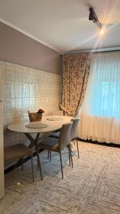 a dining room with a table and chairs and curtains at Vert Apartament in Tuzla +2 photos