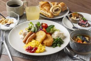 a table with plates of breakfast food and a cup of coffee at Richmond Hotel Sapporo Odori in Sapporo