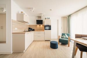 a kitchen with white cabinets and a blue chair at Am Park 16 in Prerow