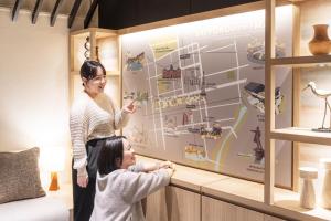 a woman and a little girl standing in front of a wall at Richmond Hotel Sapporo Odori in Sapporo