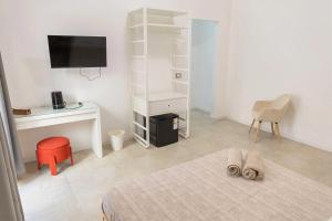 a white room with a bed and a desk and a television at Gea Guest House in Syracuse
