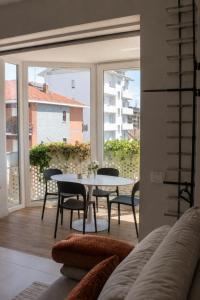 a living room with a table and chairs and a large window at GM House - Appartamento luminoso con grande terrazza vicino Torino in Collegno
