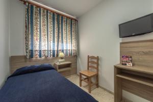 a bedroom with a bed and a tv and a chair at Hotel San Andres in Jerez de la Frontera