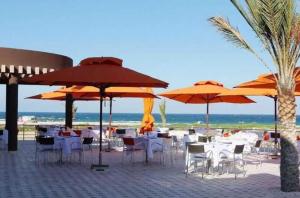 a group of tables and chairs with umbrellas on the beach at Appartement Hotel Andalucia Bizerte in Bizerte