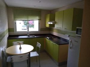 a kitchen with green cabinets and a table and a refrigerator at Appartement Hotel Andalucia Bizerte in Bizerte