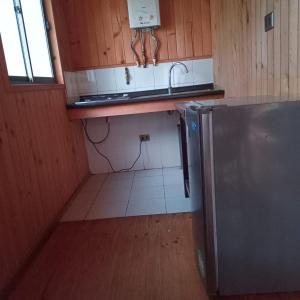 a small kitchen with a sink and a refrigerator at Posada Kalku in El Tabo
