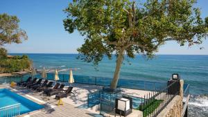 a swimming pool with chairs and a tree next to the ocean at Er Suite in Alanya