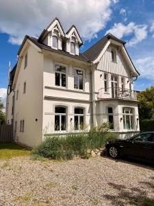 a white house with a car parked in front of it at Lilla Villa - Pá stranden - in Kellenhusen