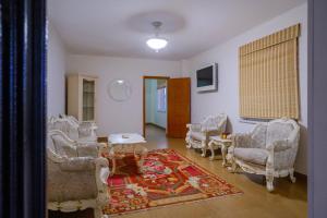 a living room with chairs and a table and a rug at Art Hotel Al Hayat in Kaji-Say