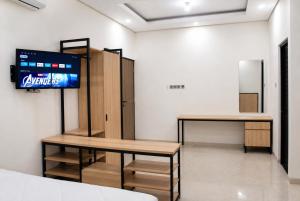 a room with two tables and a tv on a wall at Djuragan Kamar Labuhan in Semarang +2 photos