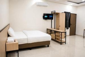 a bedroom with a bed and a television in it at Djuragan Kamar Labuhan in Semarang