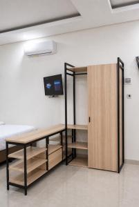 a room with a desk and a tv on a wall at Djuragan Kamar Labuhan in Semarang