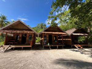 two wooden buildings with benches in front of them at Kemmi Homestay Raja Ampat in Merpati