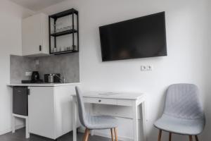 a desk with two chairs and a tv on a wall at Davin City Aparments - Self-Check-In in Hamburg