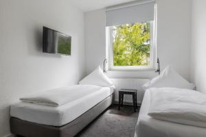 two beds in a room with a window at Davin City Aparments - Self-Check-In in Hamburg +17 photos